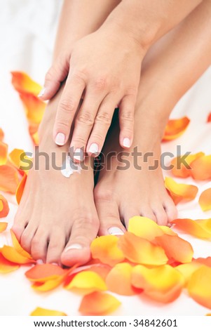 female hands and feet with petal of rose - beauty treatment