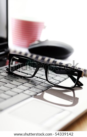 glasses with wireless mouse and laptop on desk - office life