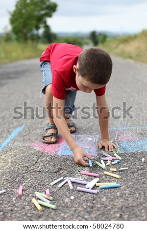 8 years old boy drawing with sidewalk chalk - family and kids
