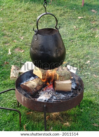 Round black cooking pot hung over fire
