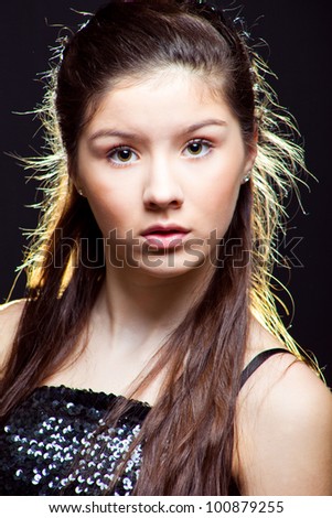 beautiful  teenager girl with long dark hair wearing sparkling dress on black background