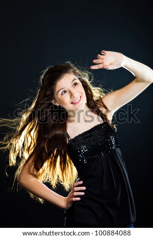 Portrait of cute girl with dark long hair lasting towards to light on black background