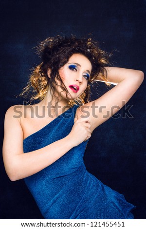 beautiful girl in turquoise dress playing with hair on blue background