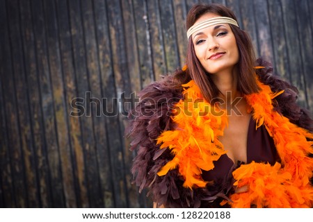 beautiful actress girl in brown and orange boa against old wooden gate