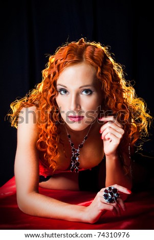 Sexy girl with red hair wearing  amber ring and necklace on black