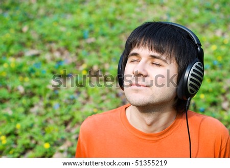 Man in headphones listening to music. Green nature background