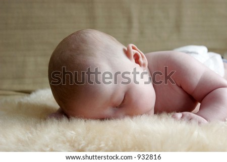 Baby boy sleeping on a sheepskin rug