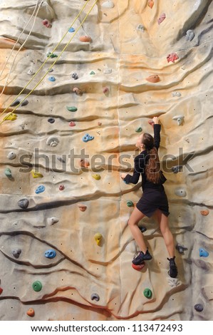 active young business woman on rock wall in sport center