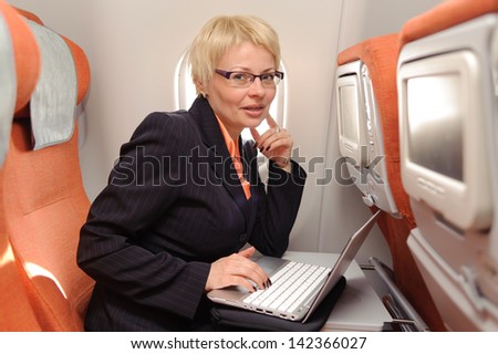businesswoman posing with laptop on the board of plane in ecomomy class of aeroflot