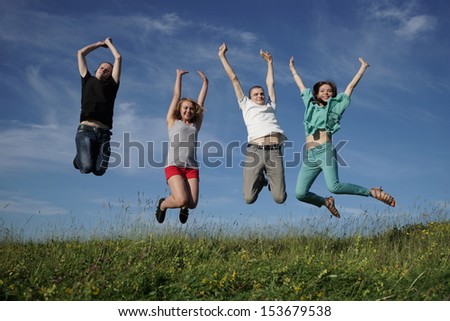 Happy group of jumping people on grean meadow