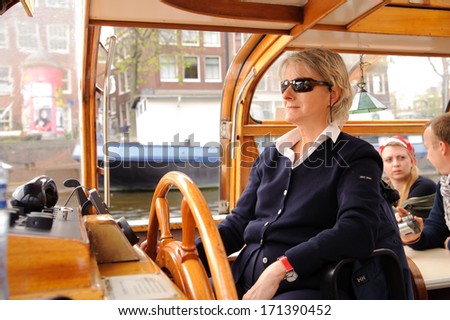 AMSTERDAM, NETHERLANDS - 18 MAY: woman drive boat on canals of Amsterdam on 18 May 2009 in Amsterdam, Netherlands. Amsterdam is the capital and most populous city of the Netherlands.