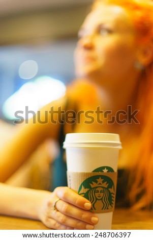PARIS - SEP 09: young woman in Parisian Sturbucks cafe (focus on cup) on September 09, 2014. Starbucks is the largest coffeehouse company in the world, with more then 23000 stores