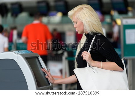 HONG KONG - JUNE 02, 2015: blonde woman using self check-in kiosk. Self Check-in service offers the opportunity to save time avoiding the check-in counter queues