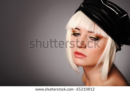 close up portrait of model with blonde hair and black peaked cap, isolated on grey. may be use for fashion cards and posters