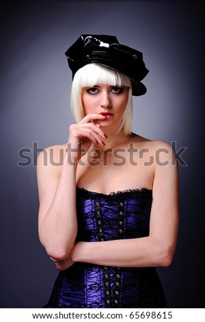 portrait of model with blonde hair and black peaked cap, isolated on grey.