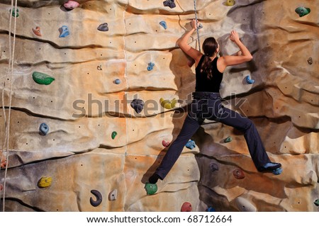 active young woman on rock wall in sport centre
