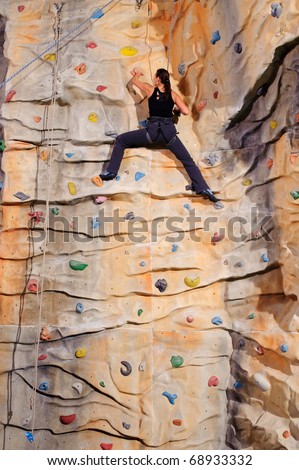 active young woman on rock wall in sport centre