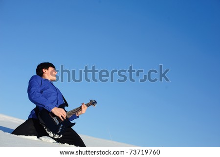 Musician playing on electro guitar in the snowdrift