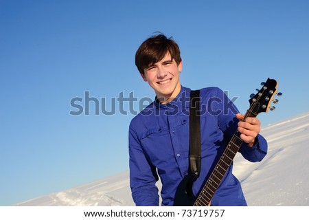 Smiling musician with electro guitar on the winter nature