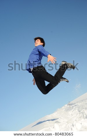jumping young teenager in blue shirt and black jeans