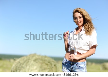 portrait of beauty blonde woman stay on green field with haystacks