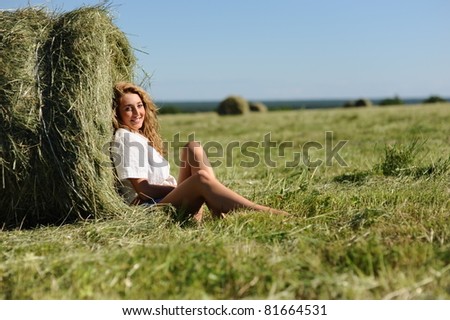 beauty blonde woman sit near haystack on green field