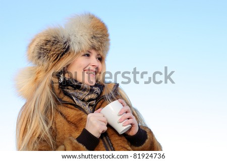 Smiling woman with cup of tea in the arms looking in the distance
