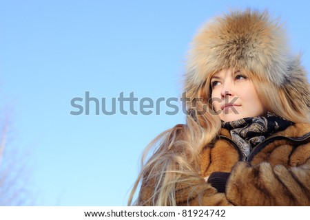 Sad woman in the fur coat and fur hat looking in the distance