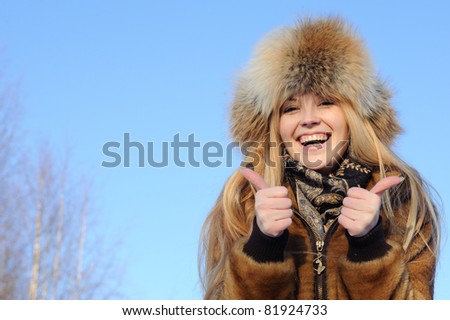 Happy woman with gesture means ok on the blue sky background