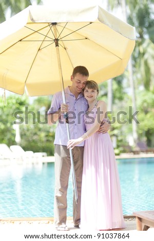 couple with big sun umbrella stay near swimming pool