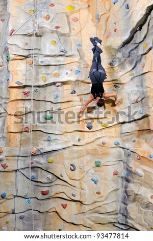 active young woman on rock wall in sport center