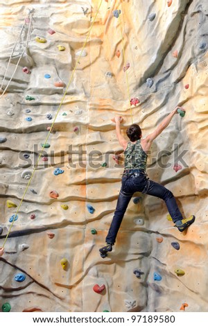 active young man on rock wall in sport center