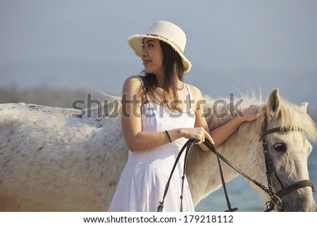 a Chinese woman walking with horse on beach