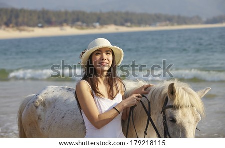 a Chinese woman walking with horse on beach