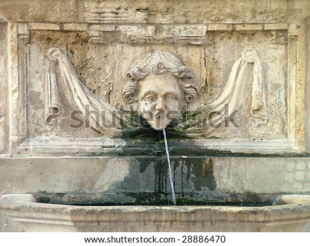 A limestone face water fountain in a garden