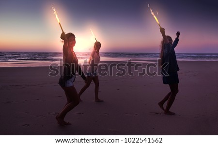 Best friends running on the beach celebrating the summer with fireworks