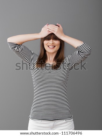 Woman smiling with hands in the head and covering eyes with her hair
