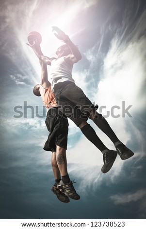 Two Basketball Players Playing Street Basket And Jumping Together To Catch The Ball