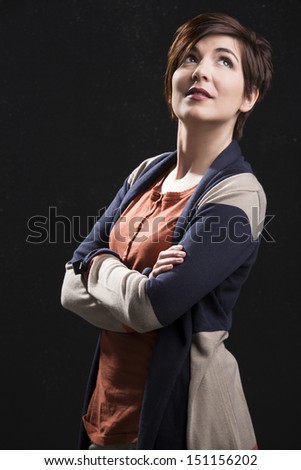 Beautiful woman with a modern hair cut and thinking, standing over a dark background