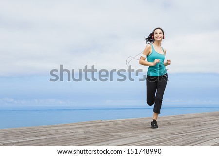 Beautiful young woman jogging on a boardwalk and listen music Beautiful young woman jogging on a boardwalk and listen music