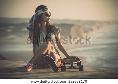 Beautiful Young Woman Sitting Over A Skateboard