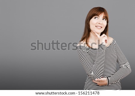 Beautiful young woman over a gray background thinking in something