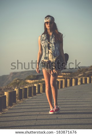 Beautiful skate girl walking while holding a skateboard