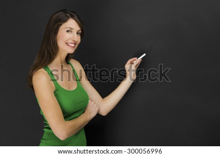 Beautiful young student over a black chalkboard with copyspace