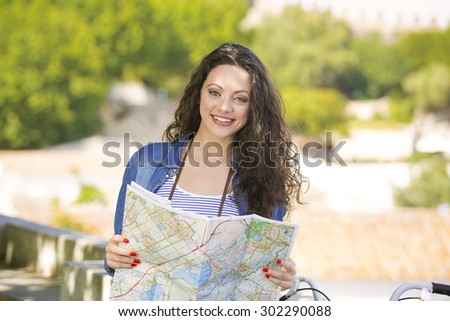 A young and beautiful female tourist searching a place on the map