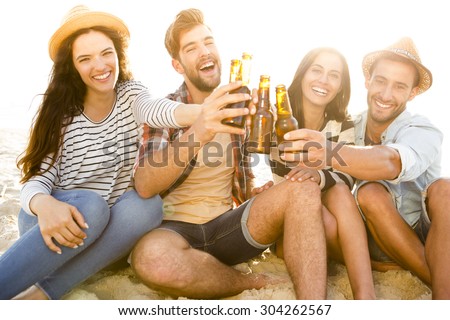 Friends having fun together at the beach and drinking a cold beer