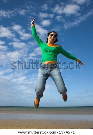 Young beauitiful woman making a big jump on the beach