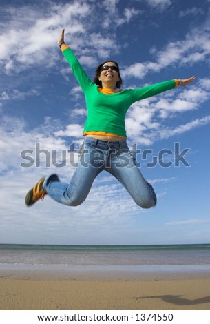 Young beautiful woman making a big jump on the beach