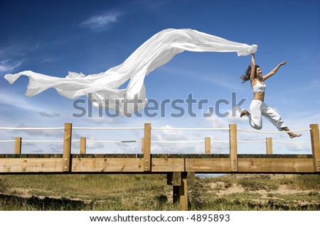 Young beautiful woman jumping with a scarf in a beautiful day