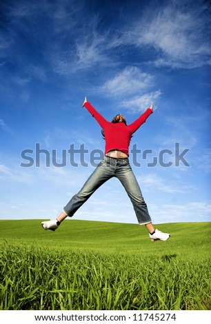 Woman making a big jump on a beautiful green meadow